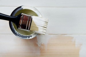 Open Paint Can Milky White Colour and Brush. Part of wooden bakground is already painted.